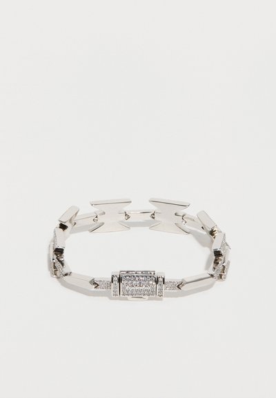 Ασημένιο μεταλλικό βραχιόλι με γωνιώδεις συνδέσμους και κεντρική ορθογώνια διακόσμηση με μικρές λαμπερές λεπτομέρειες. Λείο, γυαλισμένο φινίρισμα.