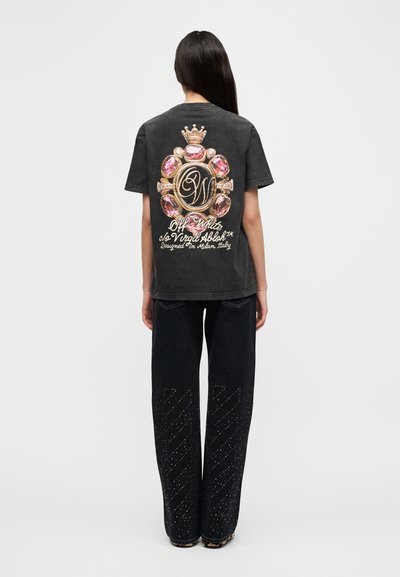 Μαύρο t-shirt κοντομάνικο με πολύχρωμο γραφικό σχέδιο με πολύτιμους λίθους και κορώνα στην πλάτη. Συνδυάζεται με μαύρο τζιν παντελόνι με καρφιά.