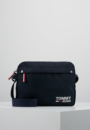 Granatowa torba na ramię Tommy Jeans z regulowanym paskiem, przednią kieszenią na zamek i logo z czerwonymi, białymi i niebieskimi akcentami.