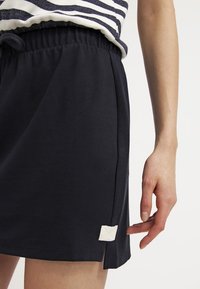 Námořnická sukně z bavlněné směsi s elastickým pasem, s bočními rozparky a texturovanou off-white etikettou na lemu pro detail.