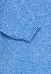 Tessuto a maglia di un blu chiaro morbido con dettagli di polsino a coste, che mostra la texture e il motivo a maglia di una manica di maglione.