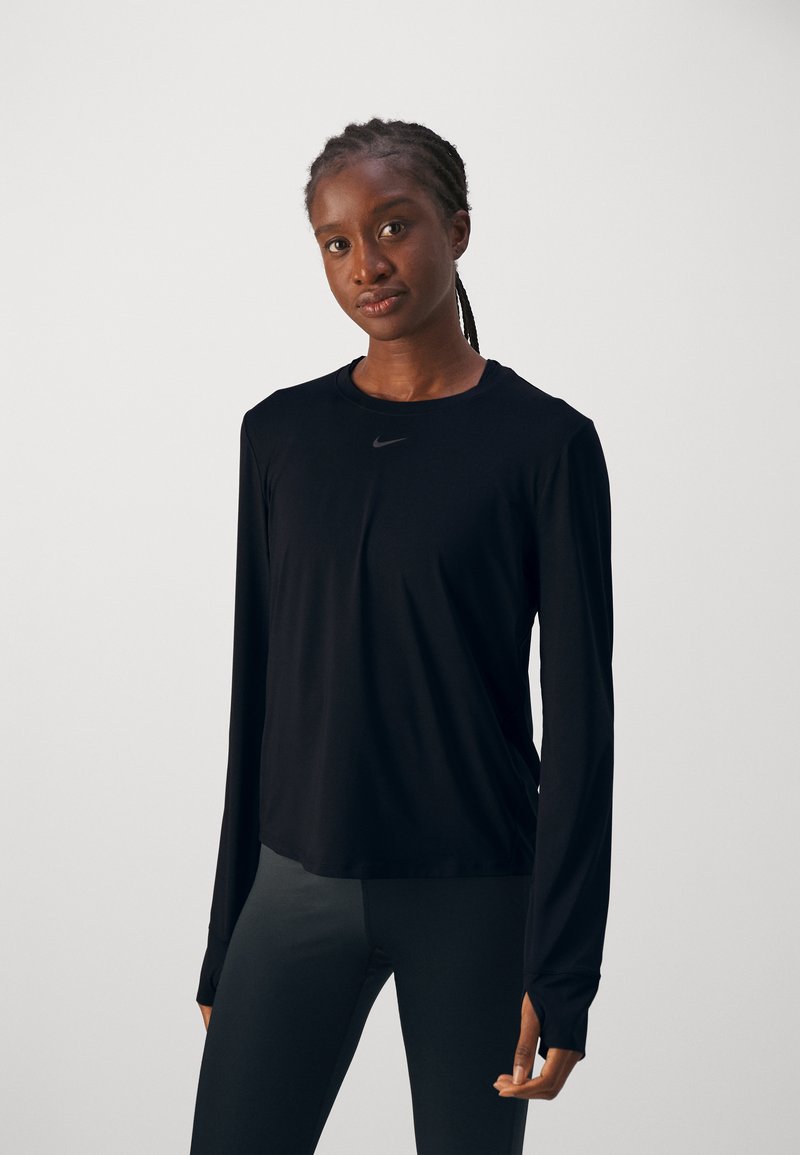 Camiseta atlética negra de manga larga hecha de tejido ligero, con cuello redondo y sutil logo de Nike en el pecho. Textura suave.