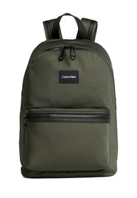 Zaino in nylon verde con cerniere nere, dotato di una tasca frontale e un'etichetta rettangolare. Spallacci imbottiti per il comfort.