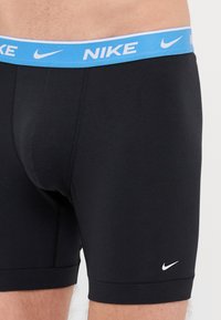 Juoda prigludusi boxeriai su šviesiai mėlynu juosmeniu, ant kurio užrašyta "NIKE" baltomis raidėmis. Priekyje yra mažas baltas Nike logotipas.