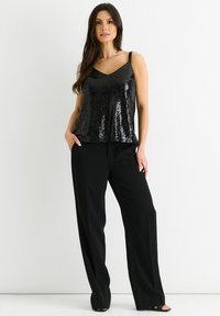 Black sequined camisole with a V-neck design, paired with loose black trousers, featuring a smooth texture and wide leg fit.