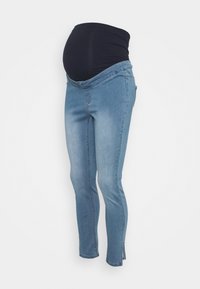Vaqueros de maternidad con una banda oscura azul sobre la barriga, denim azul claro, diseño ajustado y ligero deshilachado en los dobladillos de los tobillos.