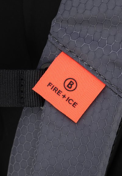 Tessuto grigio con motivo esagonale e un'etichetta arancione in evidenza con il logo "FIRE + ICE". Presenta dettagli con cinturini neri.