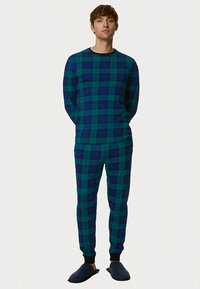 Ensemble de pyjama à carreaux bleus et verts, comprenant un haut à manches longues et un pantalon long, avec des poignets côtelés et une texture douce. Comprend des chaussons bleu marine.