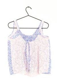 Kanten tanktop met bloemige blauwe en roze stofdelen, verstelbare bandjes en strikdetail aan de voorkant. Licht en doorschijnende textuur.