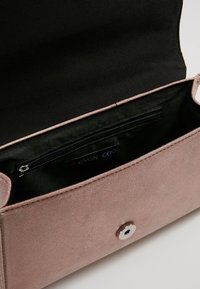 Borsa a tracolla in suede rosa chiaro con chiusura a scatto magnetico, dotata di un interno foderato in nero e una tasca con zip per una memorizzazione sicura.