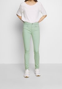 Jeans skinny de color verde claro, hechos de una mezcla de algodón, que cuentan con un diseño estándar de cinco bolsillos, cierre de botón y cremallera, y un ajuste slim.