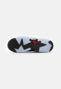 Čierna a sivá podrážka tenisiek s priesvitnou modrou časťou, ktorá má výrazné červené logo Jumpman a textúrované gripové vzory.