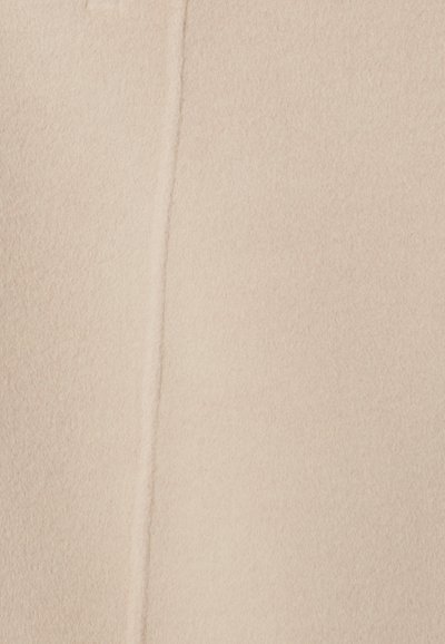Tejido de forro polar color beige claro con una superficie suave y texturizada, y un detalle de costura visible que corre verticalmente.