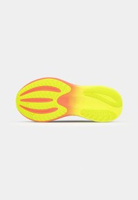 Suela de zapatilla de running en amarillo brillante y rosa, con patrones de agarre texturizados y ranuras de flexión definidas para una mayor tracción y flexibilidad.