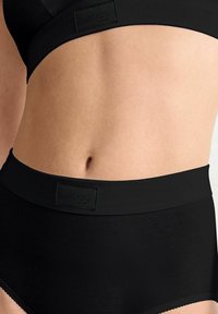 Schwarze Baumwoll-Hüfthosen mit hohem Bund und einem weichen Taillenbund, ausgestattet mit einem kleinen Logo-Label auf der Vorderseite und einer durchgehend glatten Textur.