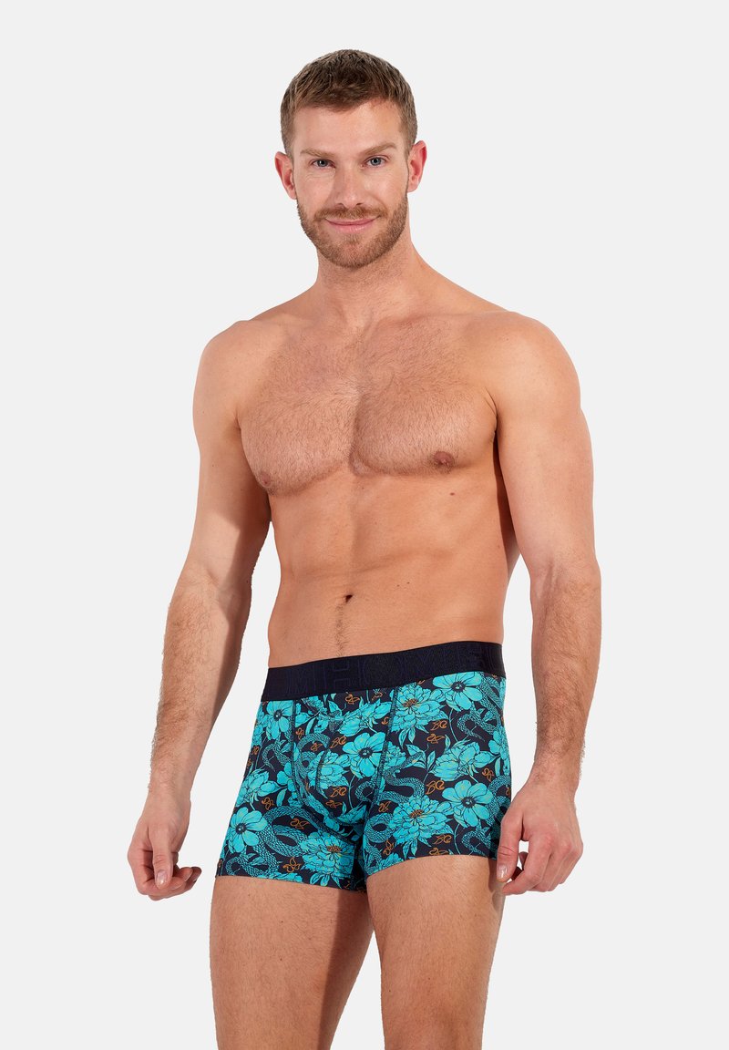 Men's boxer shorts with a dark blue base and vibrant floral pattern in turquoise and orange. Elastic waistband with textured detailing.