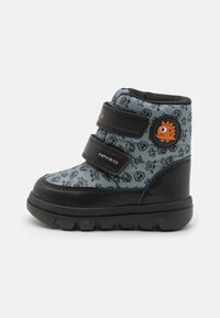 Bottes pour tout-petits en bleu et noir avec une tige texturée présentant un motif ludique. Deux bandes Velcro noires et un accent orange rond complètent le design.