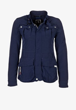 Veste bleu marine en tissu léger, avec deux poches poitrine et deux poches inférieures, fermeture éclair à l'avant et poignets ajustables.