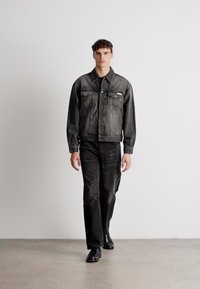 Jachetă din denim negru cu pantaloni asortați; croială clasică, două buzunare la piept și guler; textură netedă și design estompat.