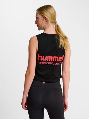 Lyshåret kvinde med hestehale iført sort ærmeløs crop top med rød "hummel PERFORMANCE" tekst og sorte leggings, vist bagfra.