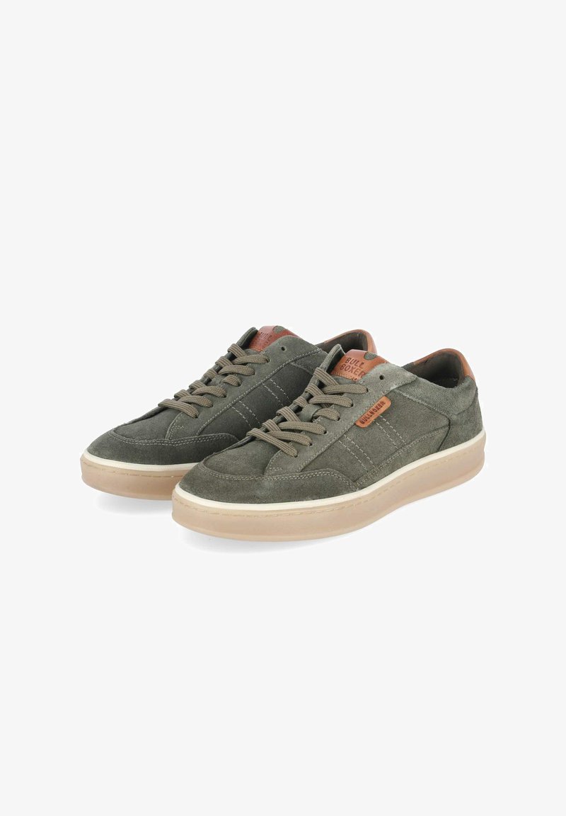 Par de zapatillas de ante verde oliva con suelas beige y detalles en cuero tostado, con cordones y etiquetas de marca en los laterales y la lengüeta.