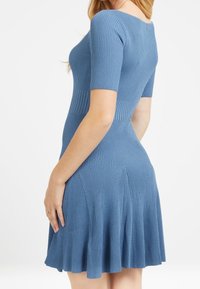 Žebrované šaty s krátkým rukávem v jemně modré barvě, přiléhavý korzet se splývavou sukní, s kulatým výstřihem a decentními švy v pase.