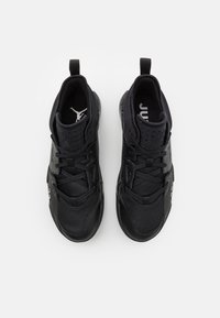 Baskets de sport noires avec une tige en maille, fermeture à lacets, col rembourré et accents de logo sur les côtés. Semelle extérieure en caoutchouc texturé.