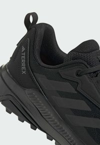 Chaussures de plein air noires avec tige en mesh, finition texturée et semelle extérieure en caoutchouc durable. Comprend un logo Terrex et une boucle pour un enfilage facile.