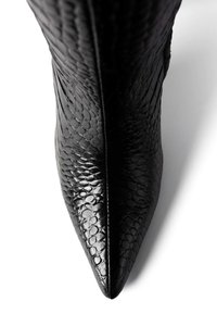 Fekete hegyes orrú csizma, amely texturált, hüllőmintás bőrből készült. Simavégű kivitel, oldalt varrással díszítve.
