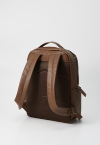 Mochila marrón con un exterior de cuero suave y paneles de malla, que presenta una forma rectangular, correas ajustables y un bolsillo con cremallera.