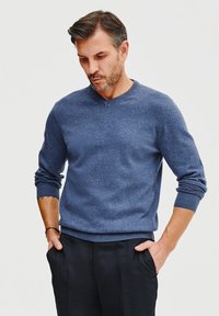 Niebieski sweter dzianinowy z dekoltem w serek, ribb rowanymi mankietami i dołem. Wykonany z miękkiego materiału, charakteryzujący się subtelną teksturą i luźnym krojem.