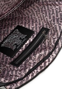 Intérieur noir d'un sac avec une doublure à motif rose comportant un texte répétitif. Comprend une étiquette en tissu noir et une poche zippée.