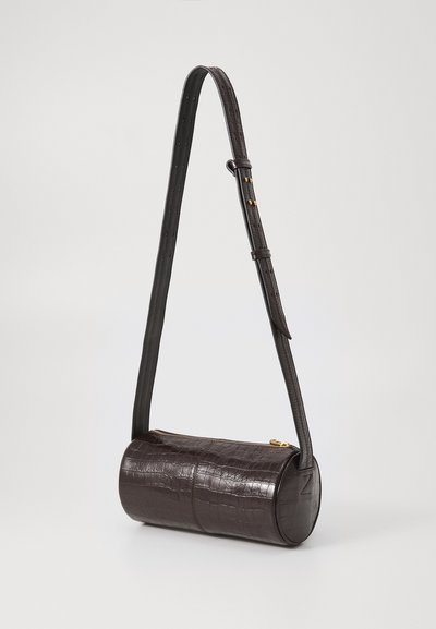 Hnedá kožená taška s krokodílím vzorom, valcovitého tvaru, nastaviteľným popruhom a zlatým zipsovým zapínaním. Hladká textúra s jemným leskom.