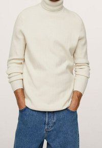 Hellbeige gerippter Rollkragenpullover mit langen Ärmeln, aus weichem Material gefertigt, kombiniert mit blauen Jeans.