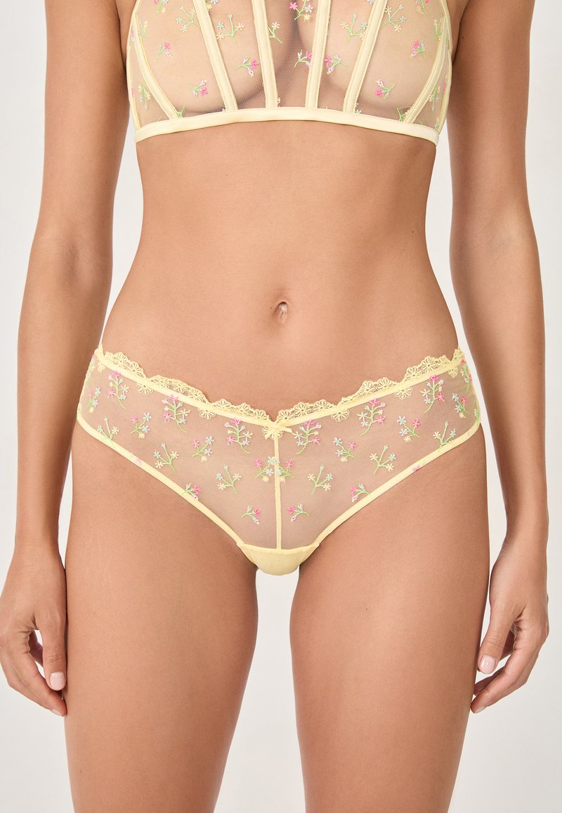 Durchsichtiges gelbes Unterwäsche-Set mit floralem Stickereimuster in Pink und Grün, zarter Spitzenborte und figurnaher Passform.