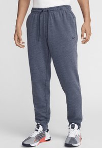 Pantalones de chándal para hombre de Nike en felpa gris oscuro, con cinturilla elástica y cordón ajustable, además de bolsillos laterales.