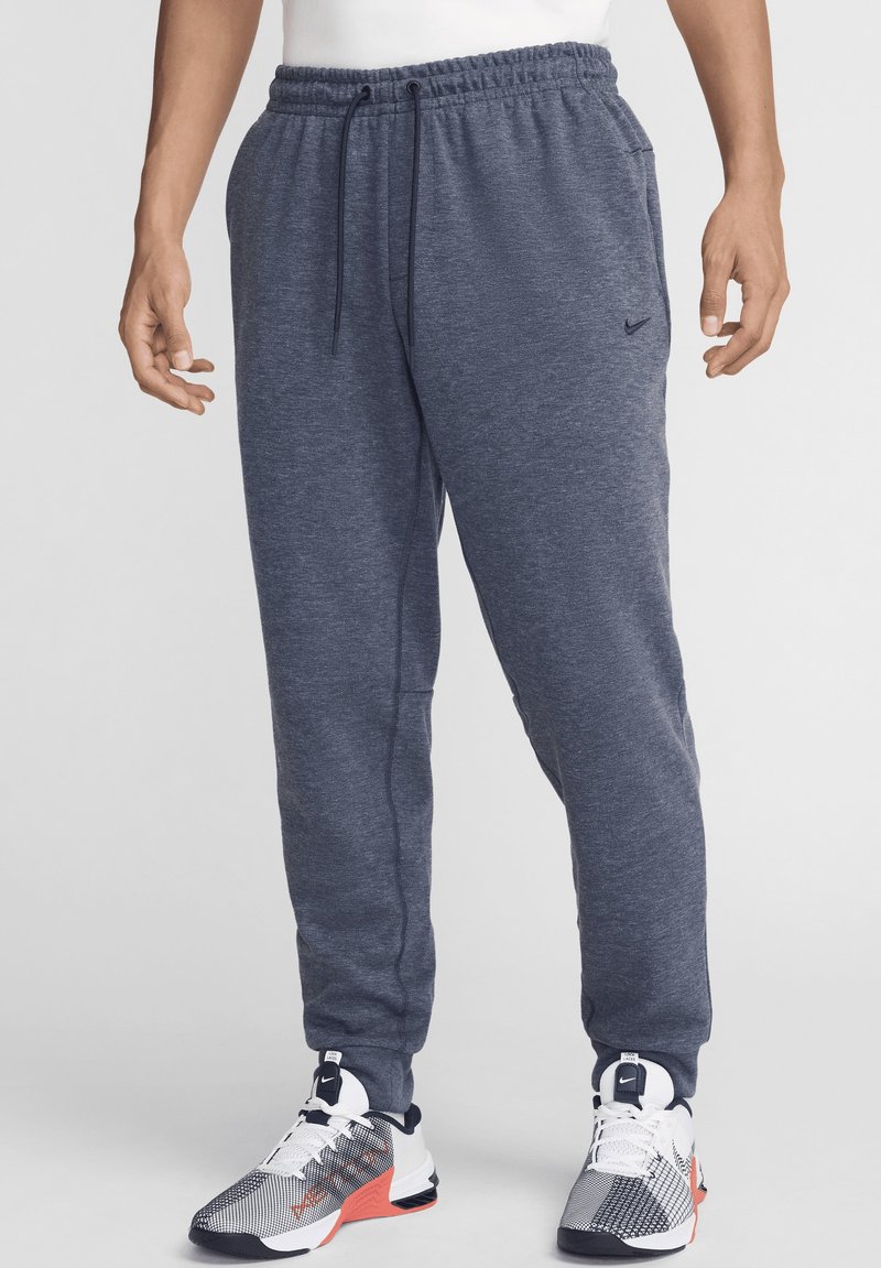 Pantalones de chándal para hombre de Nike en felpa gris oscuro, con cinturilla elástica y cordón ajustable, además de bolsillos laterales.