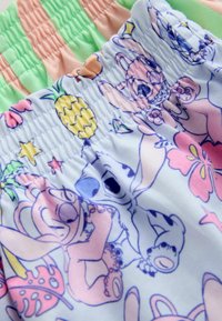 Elastisk talje med farverige tegneseriefigurer, ananas, stjerner og blomster på lag af pastelstof i grøn, pink og hvid.