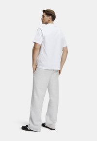 Hvit bomulls t-skjorte, løs passform, kombinert med lysegrå joggebukser, ribbestrikket linning, sidelommer, enkle svarte sandaler.