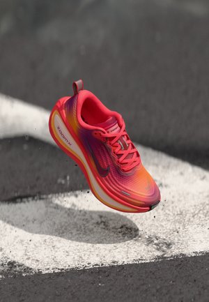 Nike ZoomX løpesko i en livlig rosa og oransje gradient, med en teksturert overdel, sikker snøring og en synlig polstret såle.