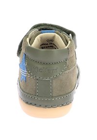 Chaussure en suede verte avec un accent d'étoile bleue, plateforme à scratch et semelle en caoutchouc beige. Présente des coutures détaillées et un marquage sur le talon.