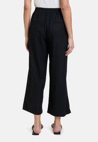Zwarte wijde broek met een elastische tailleband, twee achterzakken en een zachte, lichtgewicht stof. Casual en comfortabele uitstraling.