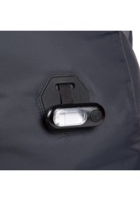 Borsa in tessuto nero con superficie testurizzata, dotata di un attacco rettangolare per una luce LED e una tracolla. I componenti metallici sono lucidi e dal design elegante.