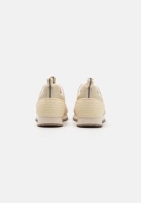 Béžové sportovní boty s síťovanými svršky, gumovými podešvemi a poutky. Texturované detaily a logo na patě. Zaoblený tvar.