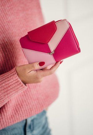 Compact wallet made of pink and red leather, featuring geometric panels, a snap closure, and a small gold accent logo.