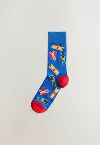 Blue sock with red heel and toe, decorated with colorful illustrations of people sunbathing and swimming on floats.