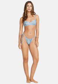Modrý bikiny set s vzorovaným braletom a nastaviteľnými ramienkami, so spodným dielom na viazanie. Vyrobené z mäkkej, textúrovanej látky.