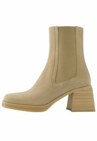 Béžová kotníková bota vyrobená z semiše, s elastickými bočními panely a texturovaným pruhovaným blokovým podpatkem. Hladký povrch, kulatý design špičky.
