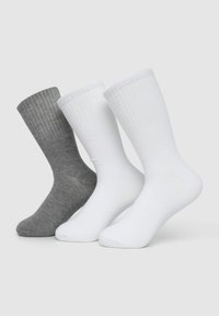 Tre calzini esposti: uno grigio scuro e due bianchi. Tutti hanno polsini a coste e un tessuto liscio con un design fino al polpaccio.