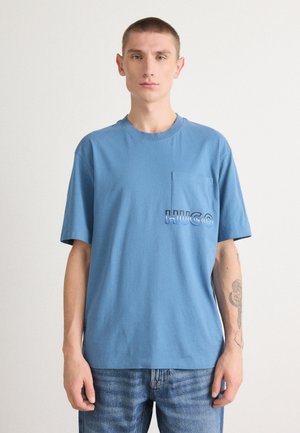 Light blue cotton t-shirt with a round neck, short sleeves, and a chest pocket featuring "HUGO" in stylized lettering. Casual fit.